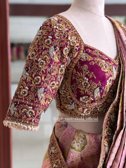 The sleeve of the magenta blouse, showing the density of the peacock and floral zardosi work.