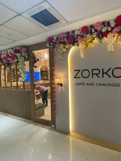 An elegant artificial floral installation framing the entrance of Zorko Cafe. This type of long-lasting decor is perfect for creating a sophisticated first impression for cafes, salons, and boutiques.