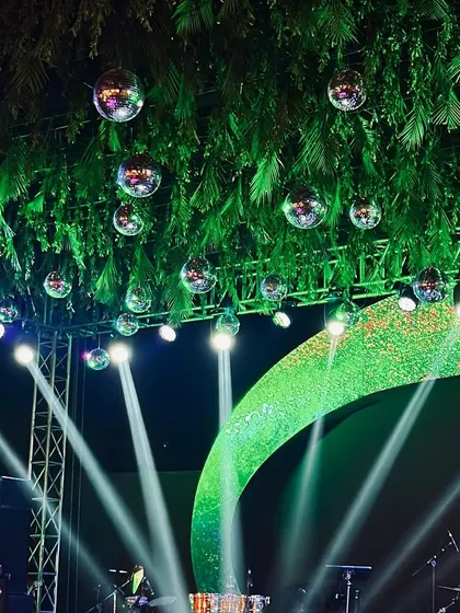 A sangeet stage with a tropical disco theme. The ceiling is covered with palm leaves and dozens of disco balls, creating a fun, glamorous, and unique party atmosphere.