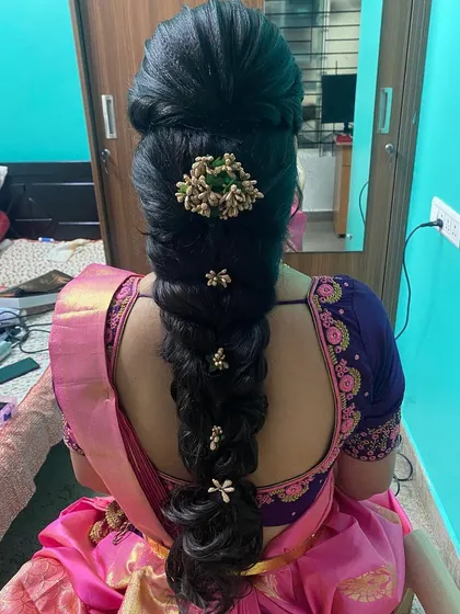 A voluminous, textured braid with a high puff at the crown, adorned with small, elegant gold floral clips.