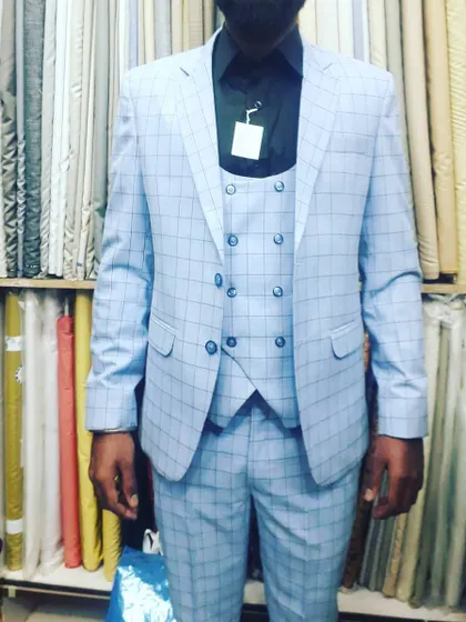 A client wearing a light blue plaid three-piece suit. The double-breasted waistcoat adds an extra layer of sophistication.