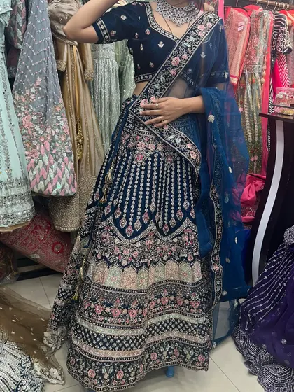 Another angle of the royal blue velvet lehenga, highlighting the detailed embroidery on the skirt and the sheer dupatta.