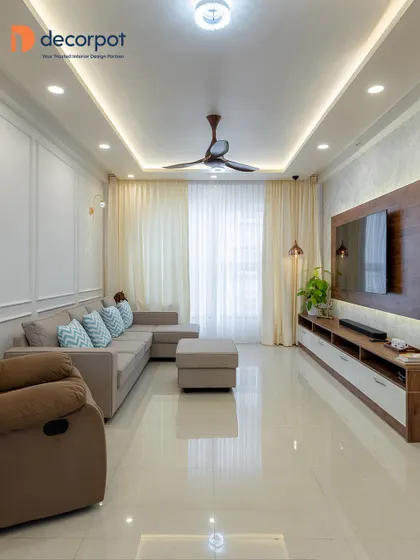 A Scandinavian-inspired living room where simplicity and comfort reign. The TV unit combines a wood back panel with a white console, perfectly complementing the neutral-toned sectional sofa and sheer curtains.