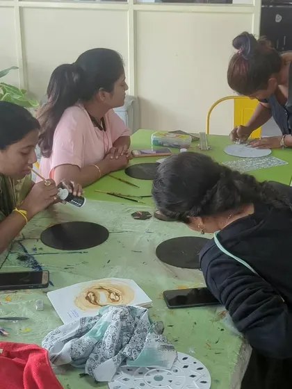Participants at a gold foil art workshop, carefully applying the foil to their designs.