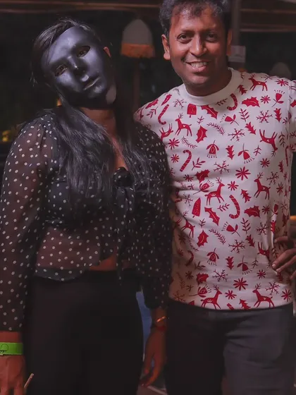 A guest in a full face mask poses with a friend at the Halloween party.