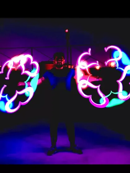 An artist holds two pixel poi, creating intricate, glowing patterns in the dark. This act is a true visual treat.