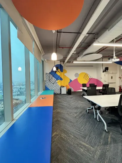A seating bench by the large windows at the Kissflow office offers stunning city views. The colorful upholstery and abstract wall art create an inspiring spot for employees to relax and recharge.