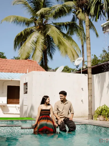 A quiet moment at the edge of the pool, surrounded by palm trees. This shot captures the relaxed, vacation-like vibe of their pre-wedding shoot location.