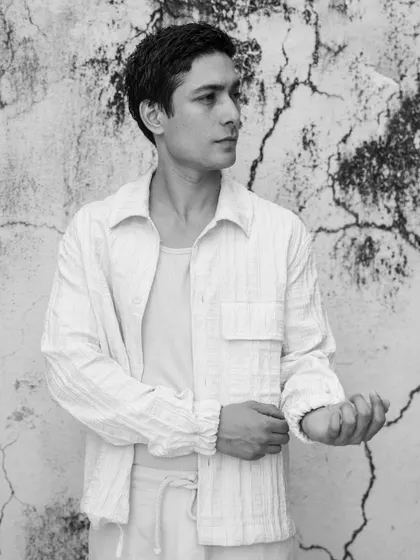 A clean and simple outdoor portrait against a textured wall. This black and white shot has a timeless feel, focusing on the model's natural look.