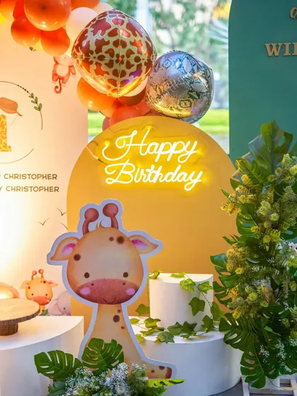 A close-up of a jungle-themed birthday, featuring a cute giraffe cutout and a glowing "Happy Birthday" neon sign. My goal is to help you live your Pinterest dreams with these picture-perfect setups.