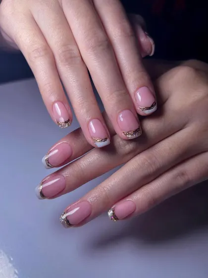 A glamorous French manicure. This design features a classic white tip with an added layer of gold glitter for a sparkling, festive finish.