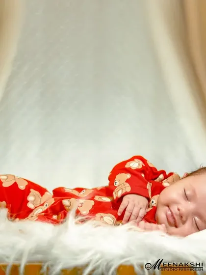 Sometimes, the simplest moments are the most precious. Here, a newborn enjoys a peaceful sleep with a tiny smile, nestled on a soft white fur blanket in a miniature wooden crib. This classic shot focuses entirely on the baby's serene expression.