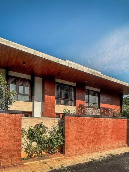 An angular view of the Hennur villa, emphasizing the dramatic sweep of the wooden-clad roof that defines the home's architectural character.