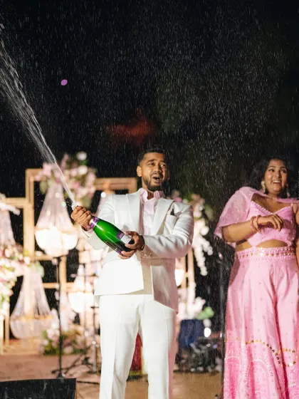 The groom pops a bottle of champagne in celebration.