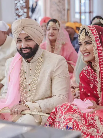 A happy, smiling portrait of the newly married Sikh couple during their ceremony. Their joyful expressions tell the whole story.