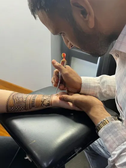 I am focused on applying a detailed wristband design. Precision and a steady hand are skills I emphasize in all my mehandi art classes.