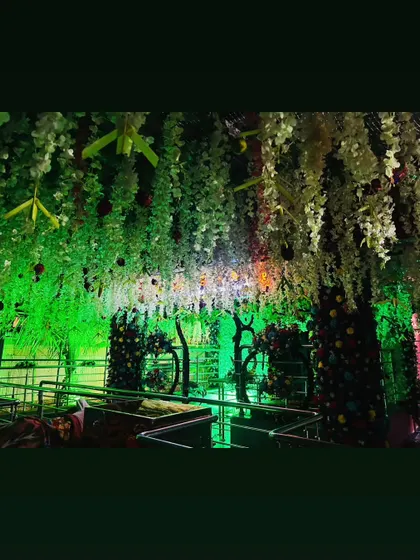 The ceiling of a temple decorated with hanging flowers and illuminated with green light, creating an immersive and divine atmosphere.