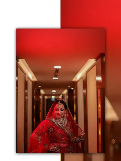 A striking bridal portrait with the bride standing in a hallway under dramatic red light. The composition and color create a bold and cinematic entrance shot.