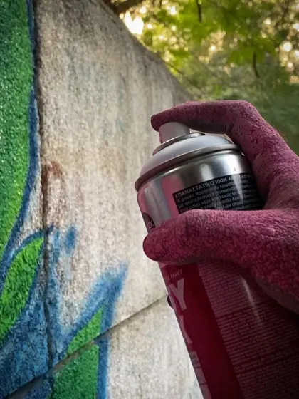 My hand, covered in pink paint, holding a spray can. Getting your hands dirty is an unavoidable and beautiful part of the painting process.