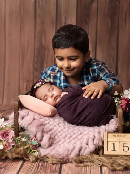 A proud big brother watches over his sleeping newborn sister. A precious moment of sibling connection.