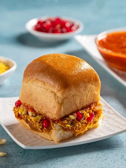 Dabeli, a sweet and spicy potato mixture stuffed in a pav bun, garnished with pomegranate and sev.