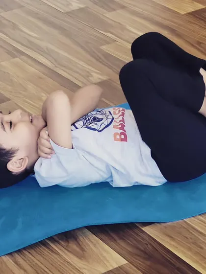 A little yogi enjoying a moment of rest and playfulness in Ananda Balasana, or Happy Baby Pose.