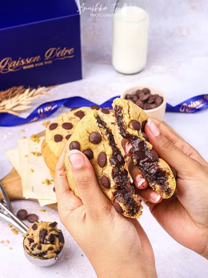 A satisfying shot of a chocolate chip cookie being broken in half to show the melted chocolate inside.
