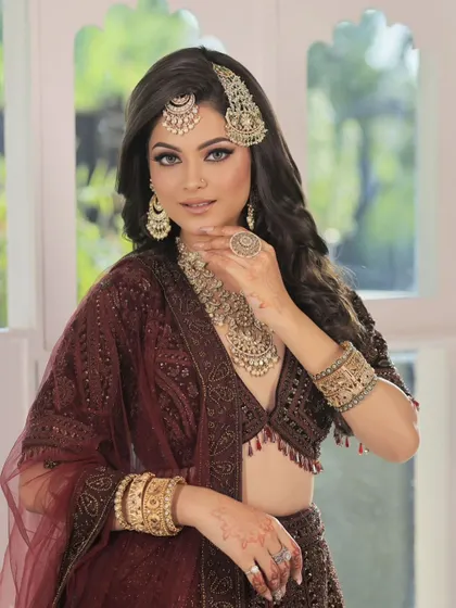Adorned in timeless elegance. This full bridal look features a heavy, traditional gold-toned jewellery set, including a layered necklace, passa, maang tikka, and oversized ring.
