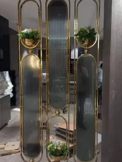 This partition uses gold-finished metal frames with integrated planters and fluted glass panels. It's a creative way to divide a space while adding greenery.
