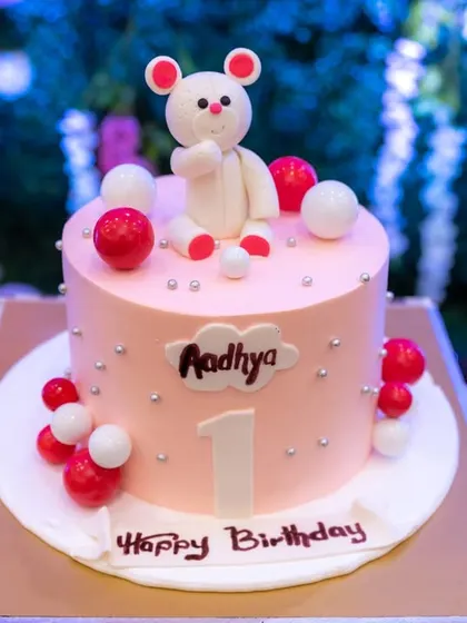 A sweet and simple first birthday cake featuring a cute bear topper. No matter the size, we believe every detail of your celebration is worth remembering.
