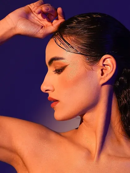 A stunning profile shot using a warm key light and a cool purple background, a classic combination for beautiful, colorful portraits.