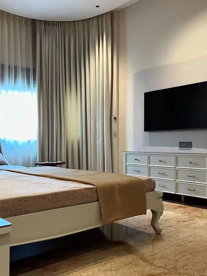 A view of the parent's room, showing the classic bed with carved legs and a simple, elegant design. The neutral color palette creates a calm and restful atmosphere.