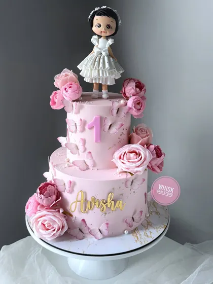 A stunning pink beauty for a first birthday. This two-tiered cake is adorned with delicate pink roses and edible butterflies for a touch of elegance.