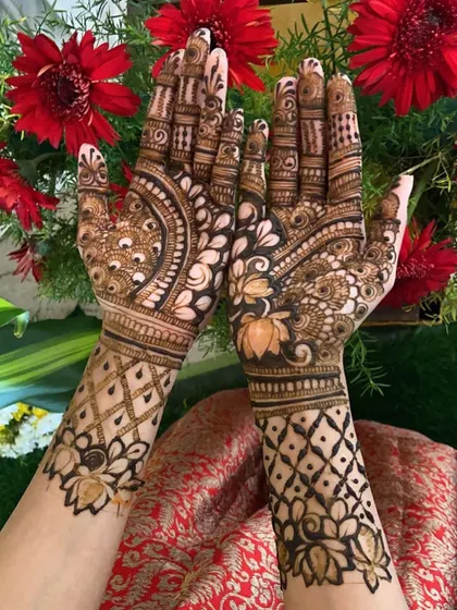 A view of both hands together, showing the complementary lotus and lattice patterns on each arm.
