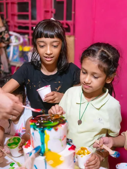 A moment of intense focus as these young chefs collaborate on their edible art project, carefully adding colorful drips to their cake.
