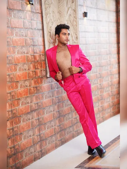 Fashion is about breaking rules. This men's fashion portrait features a bold pink suit with a mesh top, shot against a brick wall for an urban, high-fashion feel.