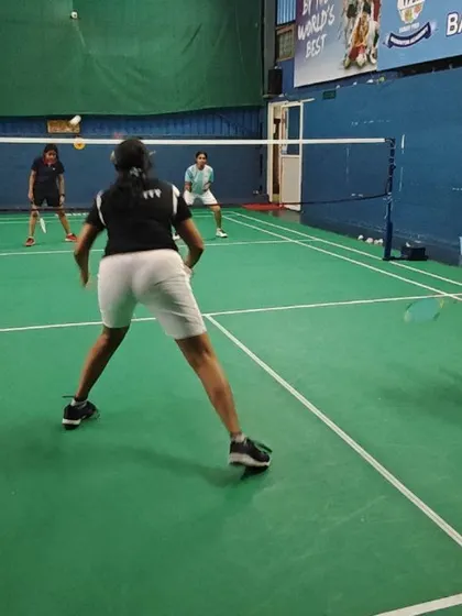 A women's doubles match in progress, showing the players in a ready stance, anticipating the opponent's shot.