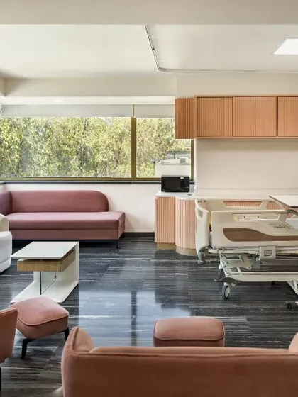 This hospital room is designed to enhance patient well-being by integrating ample natural light and a cozy seating space for family members. Thoughtful design choices create a warm and welcoming atmosphere, contributing to a positive healing experience.