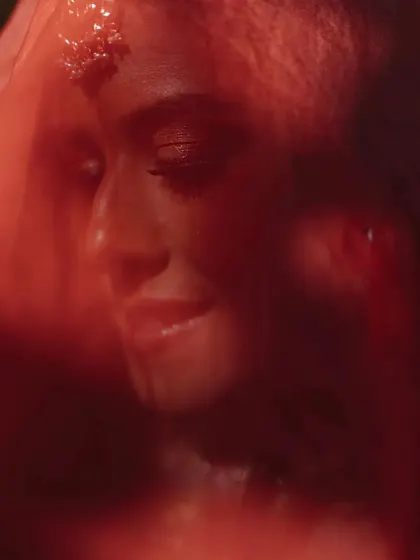An artistic and intimate bridal portrait, shot through the red veil. This creative technique adds a layer of mystique and focuses on the bride's serene expression.