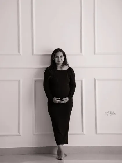 A simple yet elegant full-length portrait in monochrome. The clean lines of the wall paneling and the classic pose create a timeless feel.