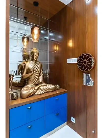 A serene entryway corner featuring a Buddha statue on a bright blue cabinet. The mirrored wall behind it enhances the sense of space and light.