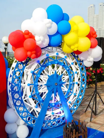 A decorative ferris wheel prop adorned with primary-colored balloons, a perfect centerpiece for a circus theme.