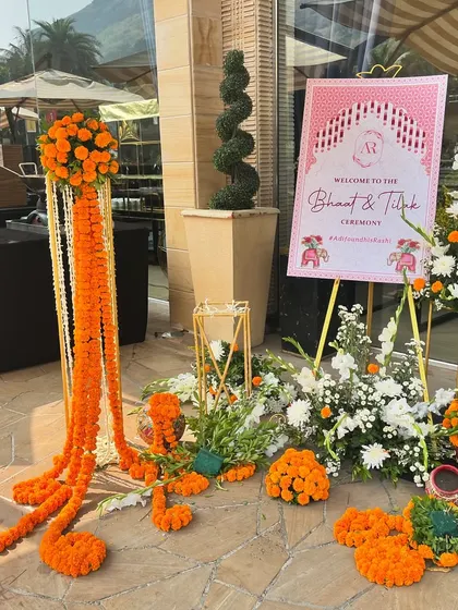 A welcome setup featuring pillars of marigold flowers. Marigolds are auspicious in Indian culture, making them a perfect choice for decorating the entrance to a traditional ceremony.
