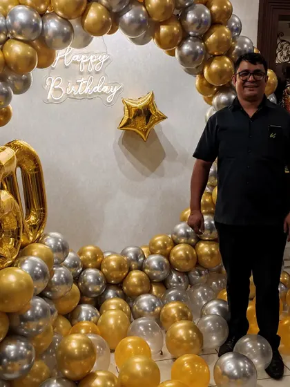 The birthday person posing happily in front of their sophisticated party backdrop.