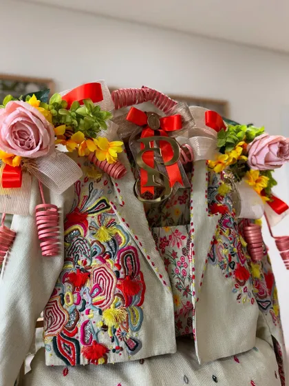 A close-up of the groom's vibrant outfit, adorned with colorful floral arrangements and playful details that match its festive energy.