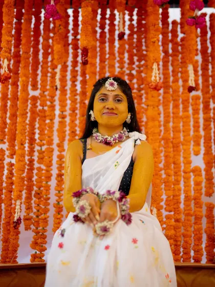 The bride glows against a classic Haldi backdrop. I created a dense wall of bright orange marigold garlands, a timeless and auspicious choice for the Harishina Shastra ceremony.