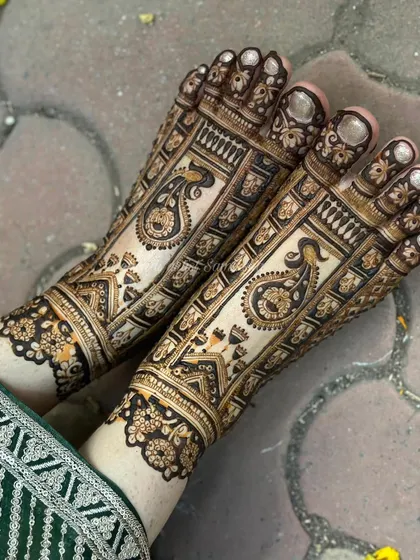 A top-down view of the intricate bridal foot mehendi, highlighting the detailed peacock and architectural motifs.