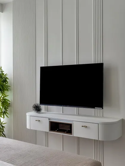 A sleek, floating TV unit elevates this bedroom's style. Its crisp white finish and the vertical paneling on the wall create a modern and clean aesthetic, proving that media storage can be elegant.