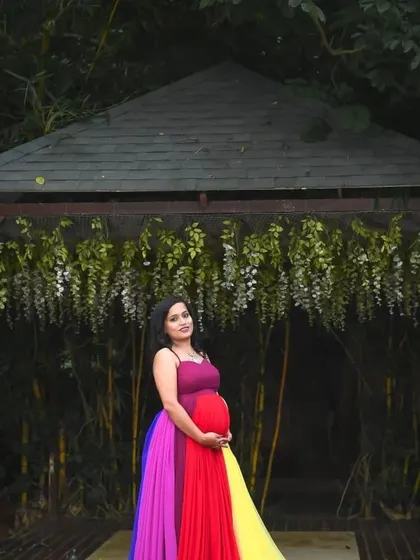 A wide shot of the rainbow maternity gown in a beautiful garden setting. The colors stand out wonderfully against the natural greenery.