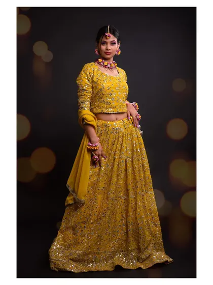 A full-length view of the yellow lehenga, showcasing the intricate mirror work and the complete festive outfit.
